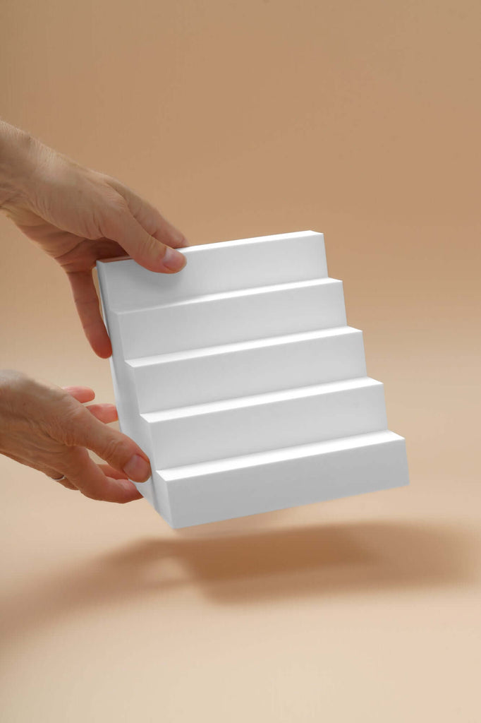 person holding a 5 step stair photography prop for product display on a neutral background