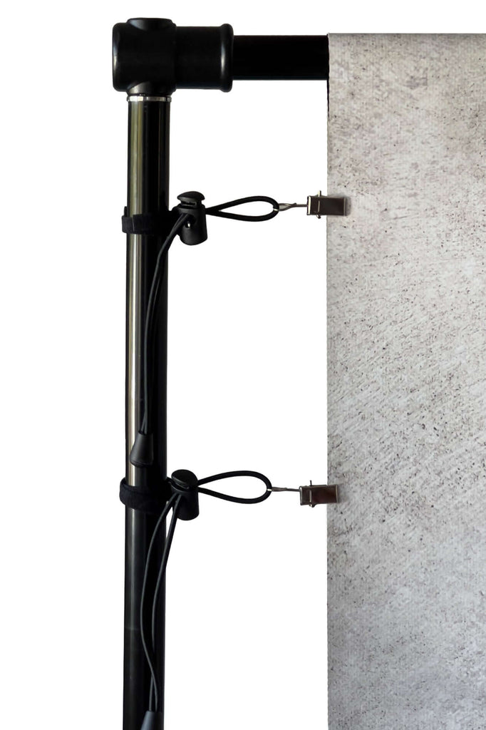 Adjustable backdrop clips securing a PVC backdrop with tension clips on a stand for optimal stability.
